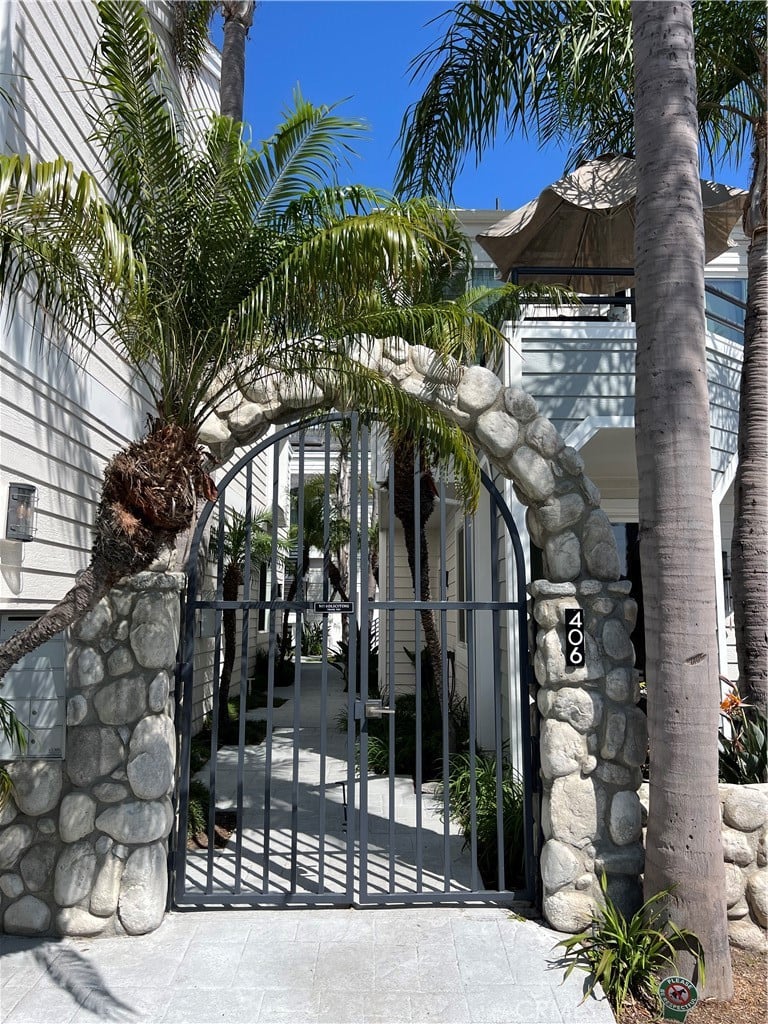An iron gate set in a stone arch between palms, with the number 406 on the pier